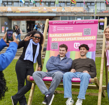 4 students posing for a photo on/next to a large deckchair