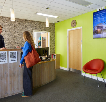 A student talking to a member of staff in the reception for accommodation support