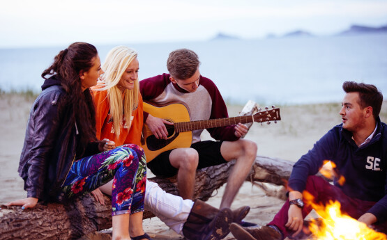 Students gathered around a fire at the beach